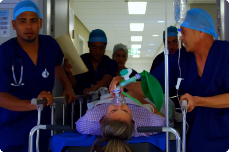 Nurses are taking a patient on a stretcher to the emergency room while the patient is wearing an oxygen mask.