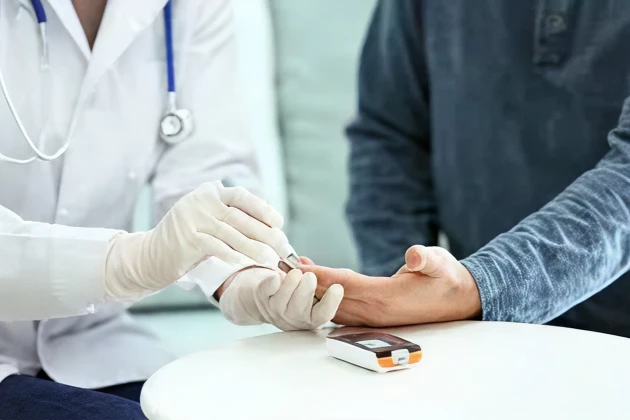 Healthcare professional checking a patient's blood sugar with a glucose meter.