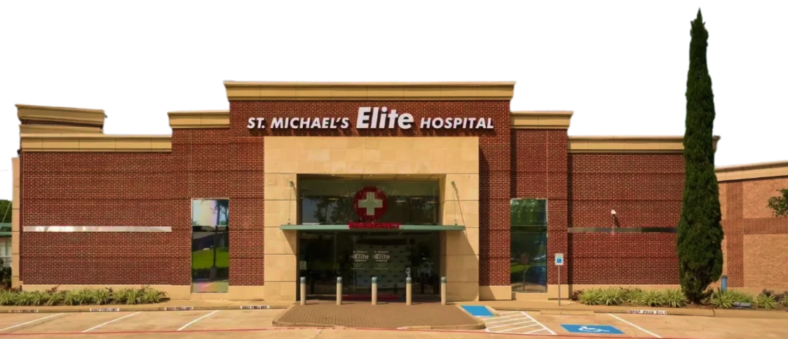 Front view of St. Michael’s Elite Hospital building with emergency entrance, red brick exterior, and accessible parking spaces.
