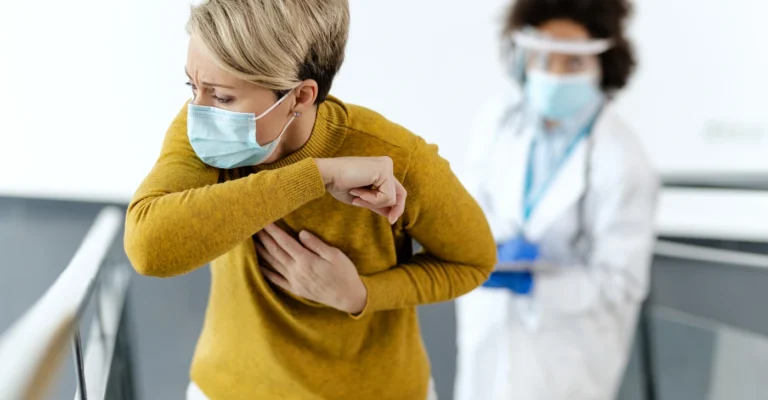 sick-woman-with-face-mask-coughing-into-elbow