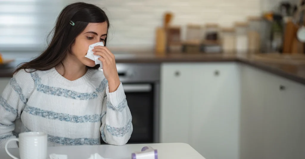 young-woman-blowing-nose-with-tissue-feeling-sick